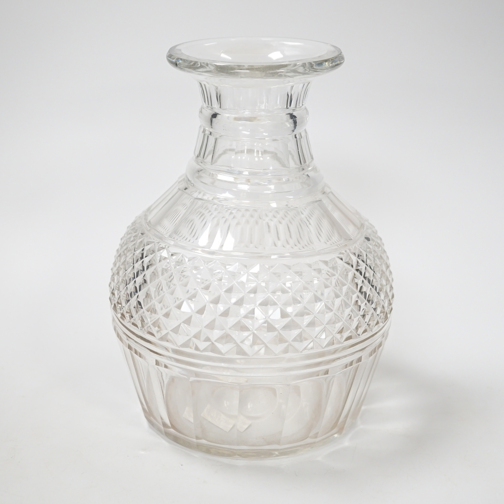 An English lead crystal Regency carafe, three rows of square cut facets alternate with two cut rings above a wide band of hobnails and further basal cut facets, ground and polished pontil, 20cm high